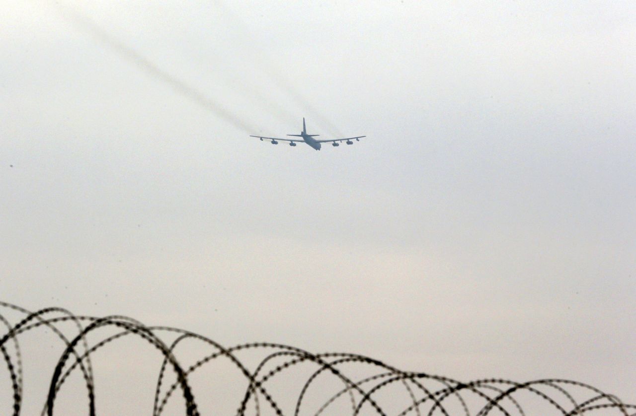 A B-52 bomber flies over the wire-topped fence of a U.S. air base in Osan, South Korea, on Tuesday, March 19.