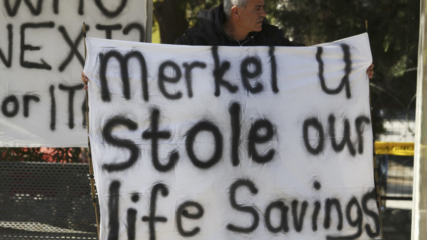 A Cypriot man holds a banner against the EU bailout deal and German Chancellor Angela Merkel.