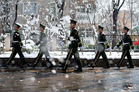Paramilitary guards walk along a street following an overnight snowfall in Beijing on March 20. 
