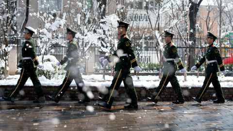 Paramilitary guards walk along a street following an overnight snowfall in Beijing on March 20.