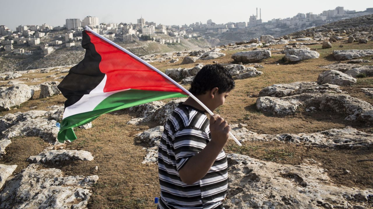 A boy waves a Palestinian flag at a camp Palestinians set up to demonstrate against Obama's visit on March 20.  Activists erected the tent city outside Jerusalem in the West Bank to protest the Obama trip and continued Israeli construction of settlements in what they consider an occupied territory.