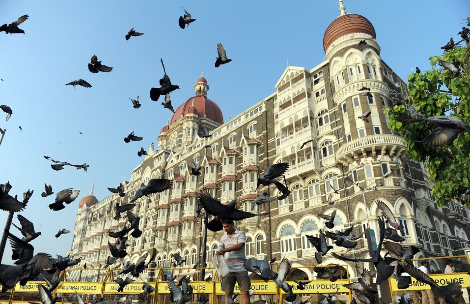 A man feeds pigeons outside the Taj Mahal Palace hotel in Mumbai, where luxury residential real estate averages £640 per square foot ($968).