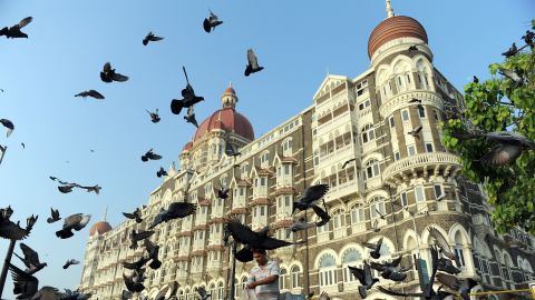 An Indian man (c) feeds pigeons outside the Taj Mahal Palace Hotel on November 26, 2010, on the second anniversary of the November 2008 terror attacks in Mumbai. 