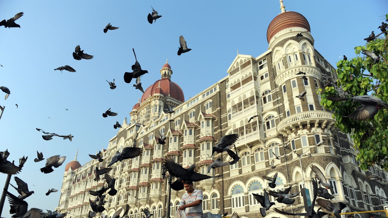 An Indian man (C) feeds pigeons outside the Taj Mahal Palace hotel on the second anniversary of the November 2008 terror attacks in Mumbai on November 26, 2010. 