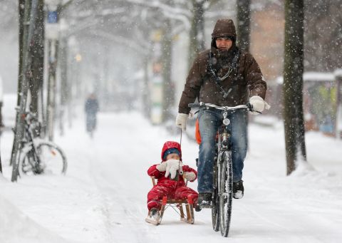 A bicyclist pulls a child on a sled through the snow on Thursday, March 21, in Berlin.