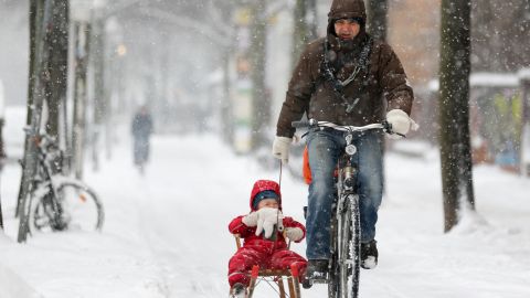 A bicyclist pulls a child on a sled through the snow on Thursday, March 21, in Berlin.