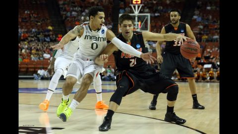 Rodrigo De Souza of the Pacific Tigers, center, moves the ball against Shane Larkin of the Miami Hurricanes on March 22.