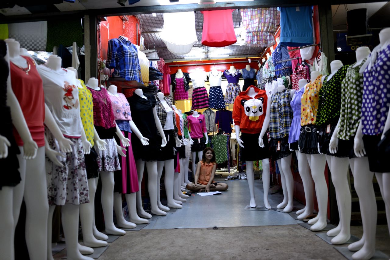  A woman sits in her shop lined with mannequins in a shopping center in Mawlamyine.
