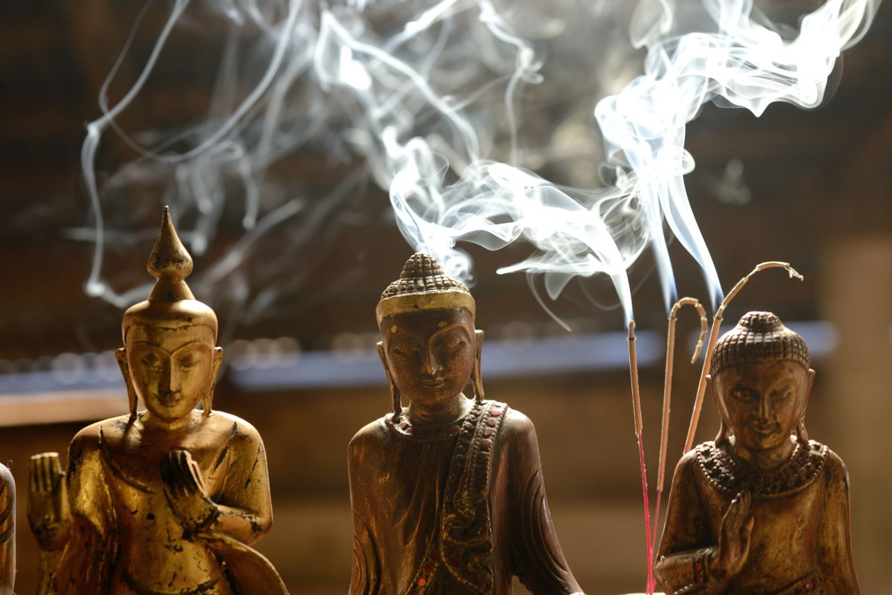 Wooden figures sit for sale as incense burns behind them at a stall in Indein, a village by Inle Lake.