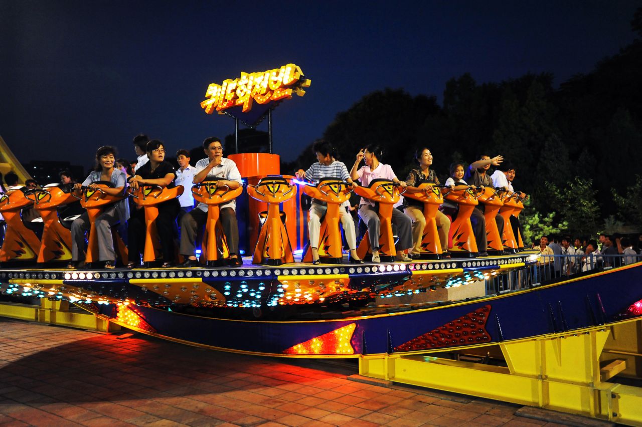 A group enjoys a ride on one of the many attractions at a funfair in Pyongyang. The city hosts new funfairs and amusement parks every night. North Koreans who can't afford the rides come just to watch.