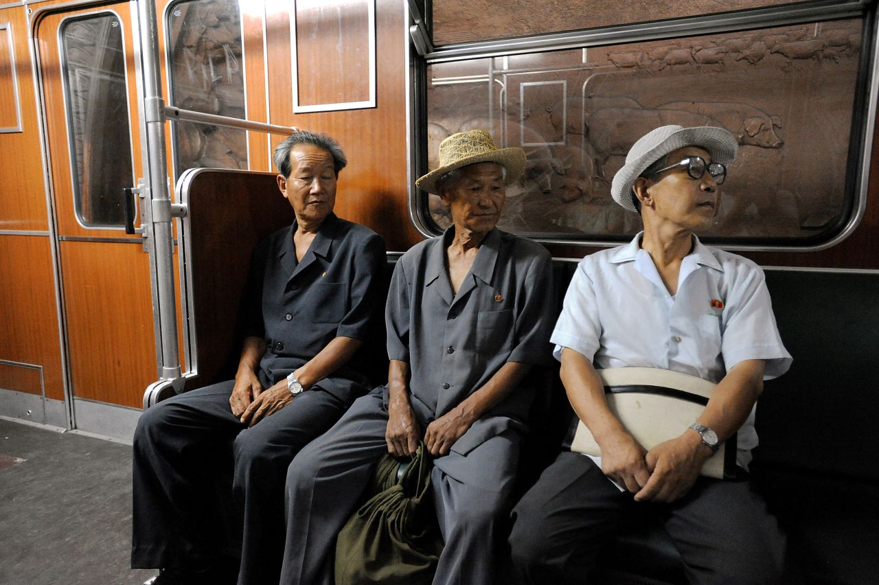 Three North Koreans ride a metro train in Pyongyang. The carriages were purchased from Germany in 1998. Not visible in this image, inside of each carriage hang small pictures of deceased leaders, neatly framed behind glass.