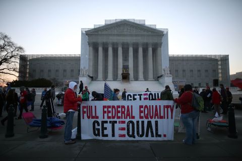Banners are held up as people gather outside the Supreme Court on Tuesday.