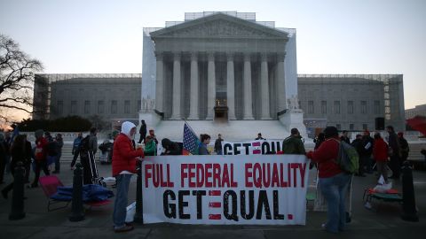 Banners are held up as people gather outside the Supreme Court on Tuesday.