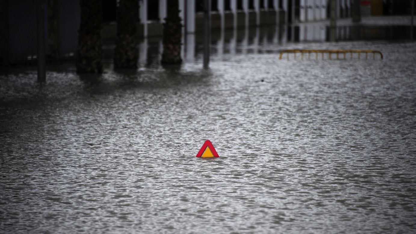 A road sign peeks above a flooded street in Badolatosa, Spain, on Monday, March 25.