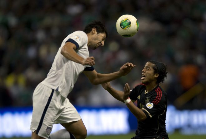 The U.S.'s Omar Gonzalez tries to head the ball as Mexico's forward Giovani dos Santos challenges.