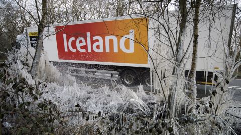 A supermarket semi-truck passes icicles and ice-covered shrubs near Hazeley Bottom, England, south of Reading, on Wednesday, March 27.