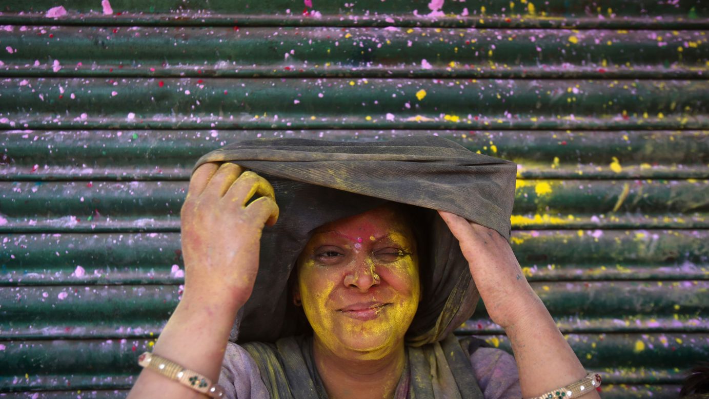 A woman squints as she looks out from under her veil after being smeared in colored powder in Vrindavan, India, on March 27.