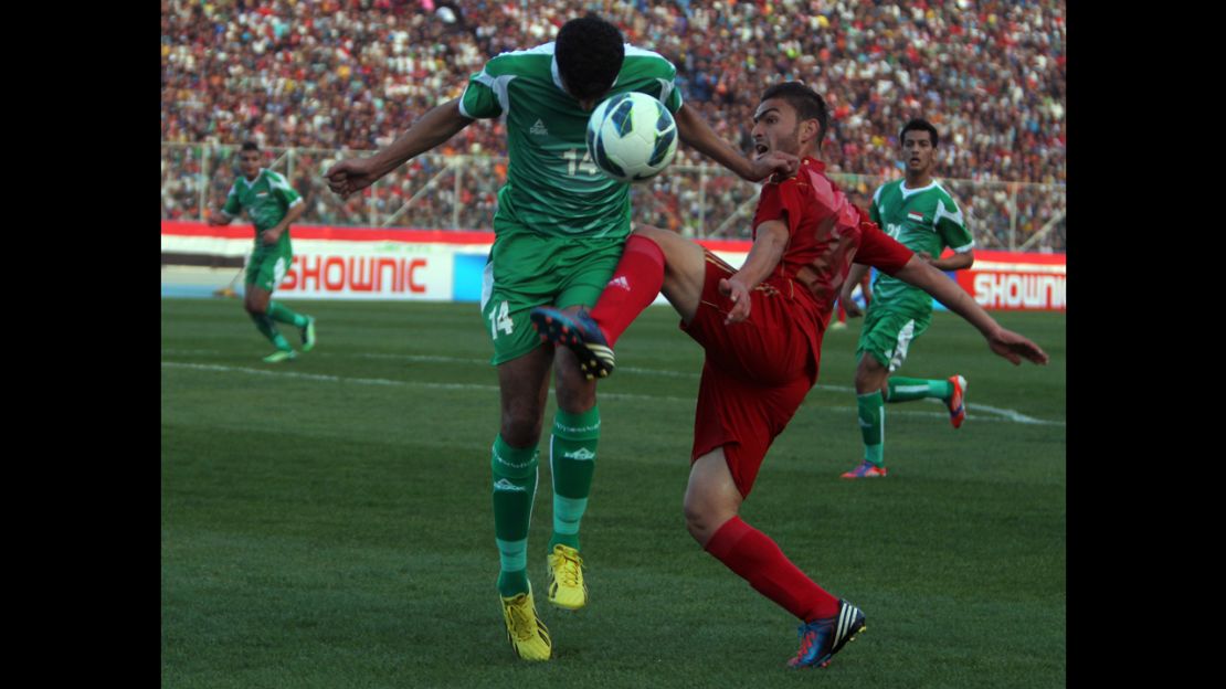 A Syrian player, wearing red, vies for the ball against an Iraqi player during Tuesday's friendly match in Baghdad.