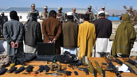 Taliban fighters stand handcuffed near seized weapons at a police headquarters in Jalalabad on March 2, 2013.