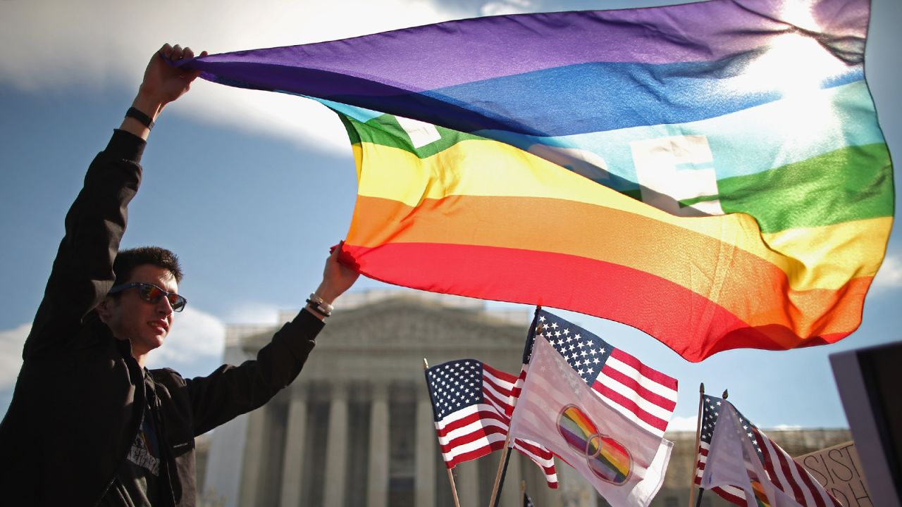George Washington University student Eric Breese waves a rainbow flag outside the court Wednesday. 