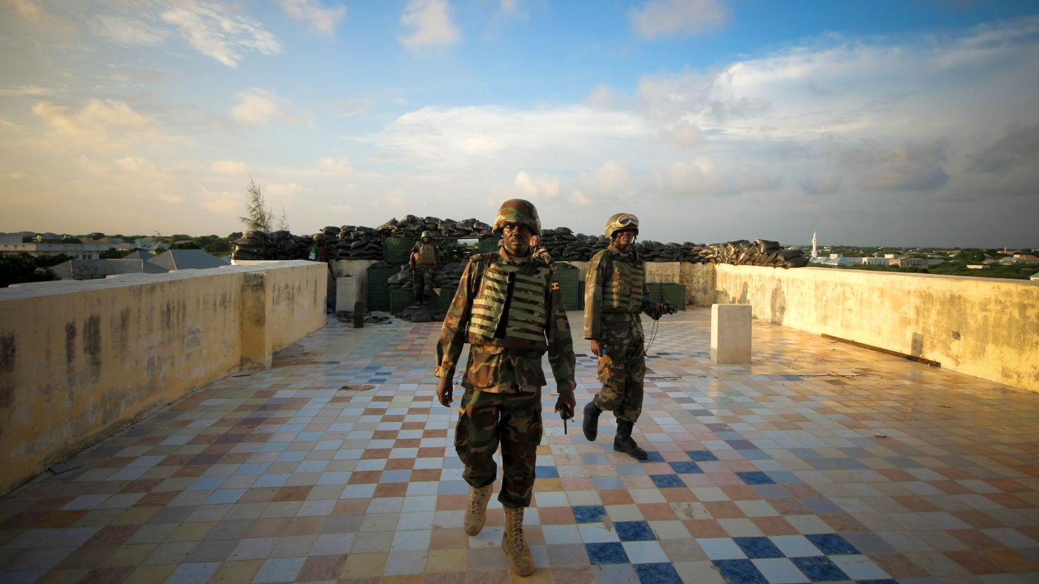 Soldiers walk across a defensive machine gun position on a hotel rooftop in the Yaaqshiid District of Mogadishu.