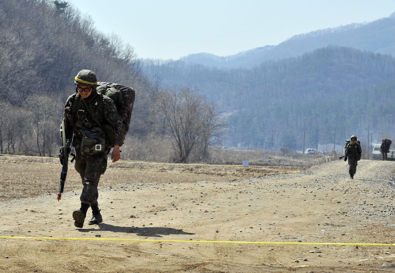 Armed South Korean soldiers walk on a road near a military drill field in Paju on March 27.