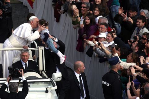 Pope Francis greets a child from an open-air jeep on Wednesday.