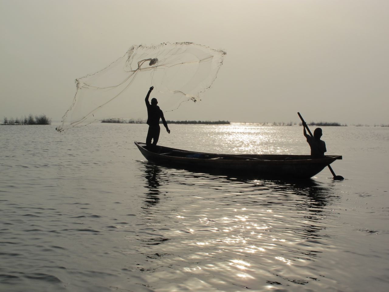 A fisherman throws out his net on the lagoon's calm waters. Fisherman immigrating from Benin and Togo initially settled Makoko over a century ago. But as the population of Lagos exploded to its current size of at least 15 million, so too did the population of Makoko. Estimates are anywhere from 85,000 to 250,000 people live there.