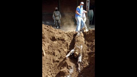 Workers unearth the bodies of three unidentified people whose killings are believed to be related to drug trafficking, according to the state police department, in Uruapan on Janurary 4, 2007.