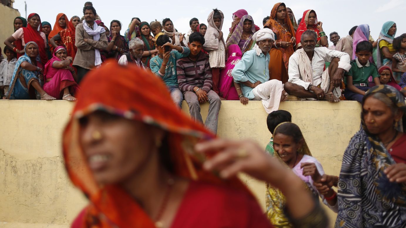 Men and women watch people taking part in huranga at Dauji temple on March 28.