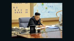 Kim Jong Un being briefed by his generals. Plan for the strategic forces to target the U.S. -- including Hawaii and California -- can be seen in background.