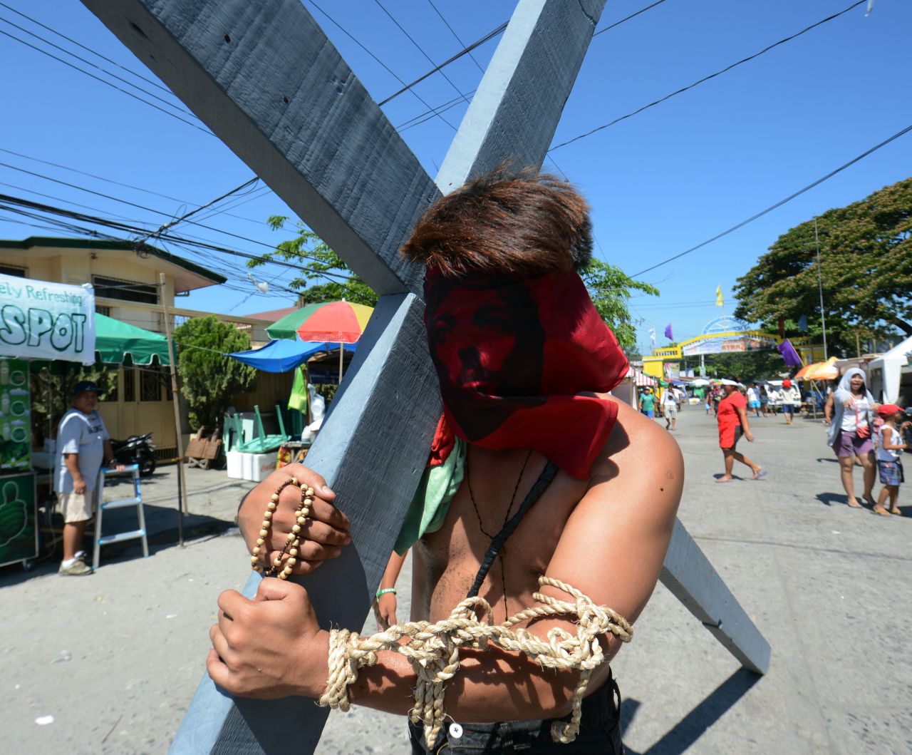 A portrait of Jesus covers a penitent's face as he carries a cross during a Holy Week ceremony in the northern province of Pampanga in the Philippines. 