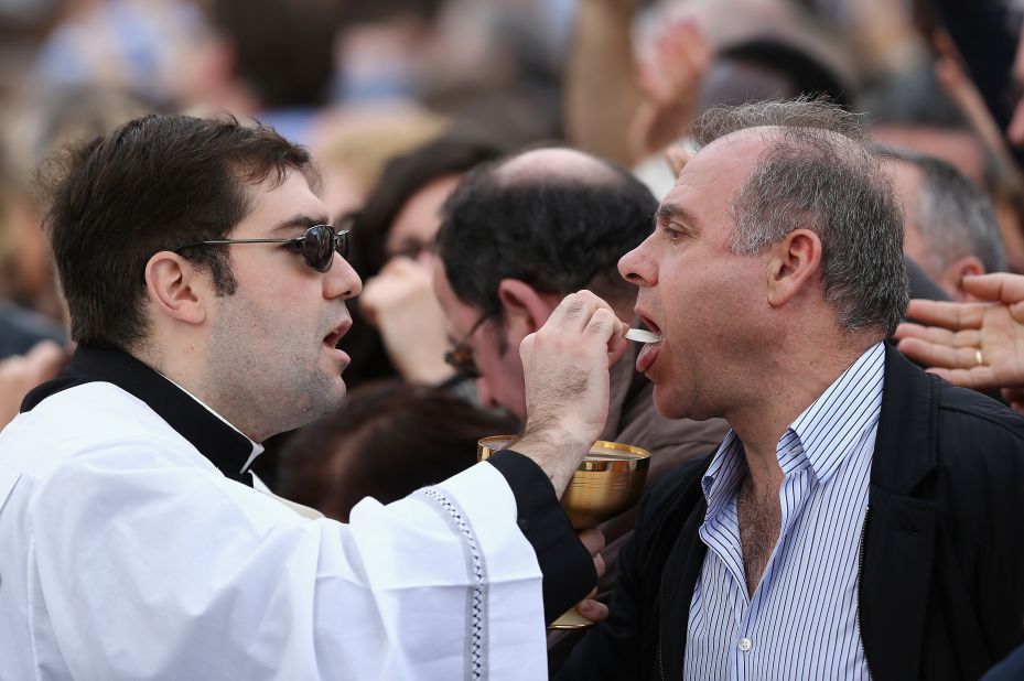 A priest gives Holy Communion to attendees as Pope Francis delivers Easter Mass on Sunday.