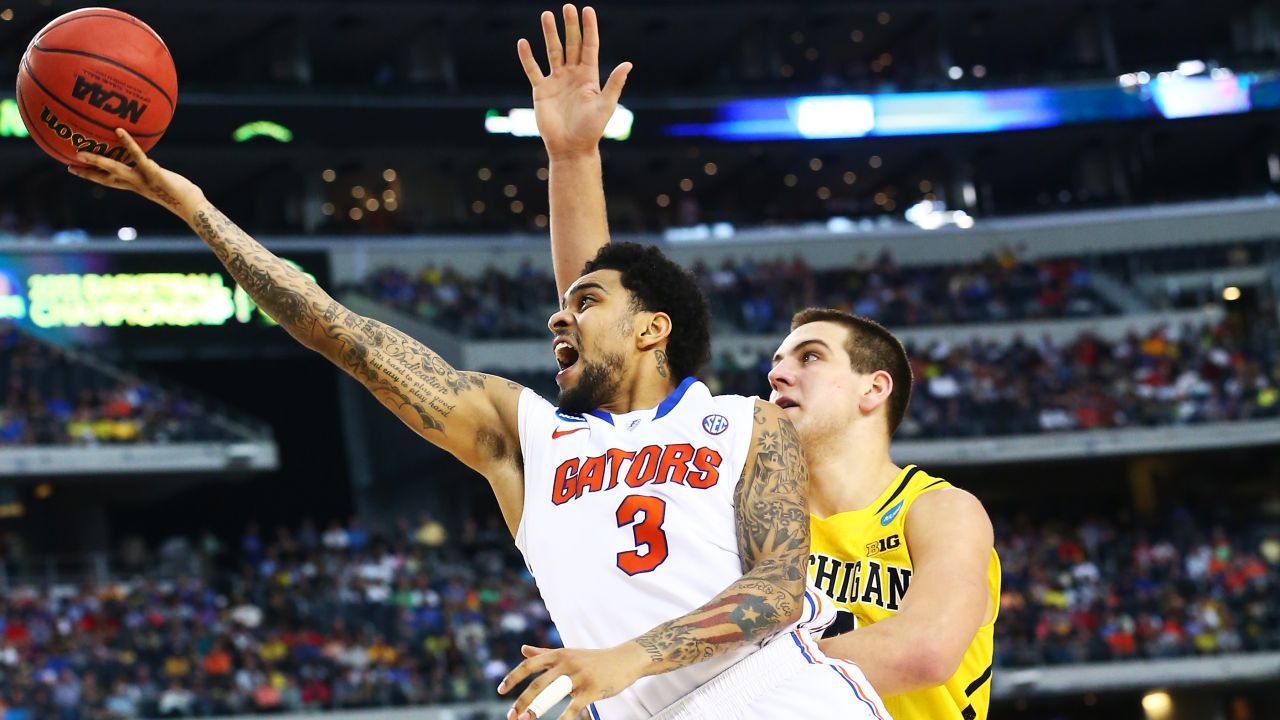 Mike Rosario of Florida shoots past Mitch McGary of Michigan.