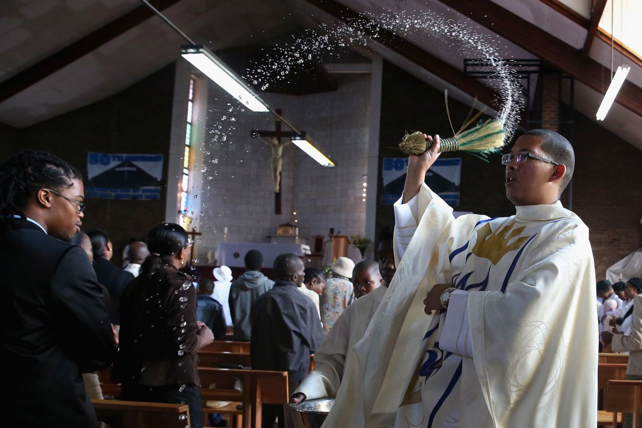 The Rev. Sebastian Rossouw O.M.I. sprinkes holy water on congregants during Easter services at Regina Mundi Catholic Church in the Soweto area of Johannesburg, South Africa, on Sunday, March 31.
