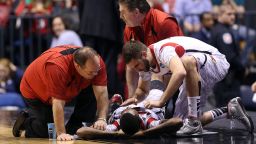 INDIANAPOLIS, IN - MARCH 31:  Kevin Ware #5 of the Louisville Cardinals talks with teammate Luke Hancock #11  as Ware is tended to by medical personnel after he injured his leg in the first half against the Duke Blue Devils during the Midwest Regional Final round of the 2013 NCAA Men's Basketball Tournament at Lucas Oil Stadium on March 31, 2013 in Indianapolis, Indiana.  (Photo by Andy Lyons/Getty Images)