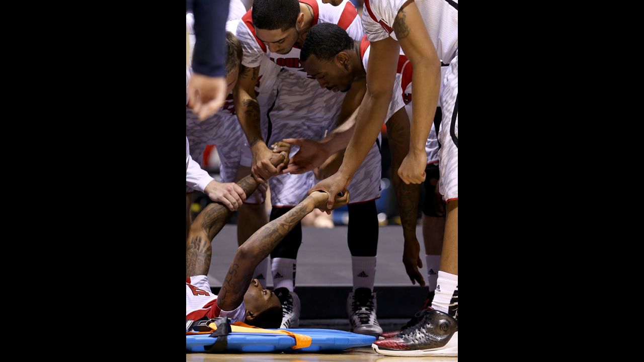Kevin Ware, bottom left, is comforted by his teammates as his leg is examined by medical staff.