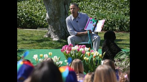 Obama sits with his dog Bo and reads a book to children.
