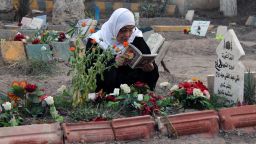 TO GO WITH AFP STORY BY JOSE RODRIGUEZ- A woman reads the Koran, the Muslim holy book, next to the grave of one relative buried in a public park on March 11, 2013 in Syria's eastern city of Deir Ezzor. Men, women and children, and sometimes fighters barely out of adolescence -- every day Al-Mashtal park in the city becomes the final resting place for new victims of the conflict that has torn Syria apart for over two years. AFP PHOTO / JOSE RODRIGUEZ (Photo credit should read JOSE RODRIGUEZ/AFP/Getty Images) 