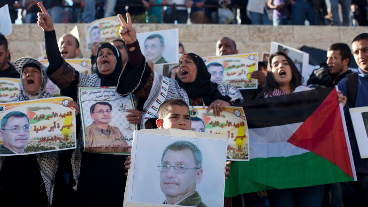 Palestinian protesters hold up photos of Maisara Abu Hamdiyeh, a prisoner who died of cancer while in an Israeli jail.