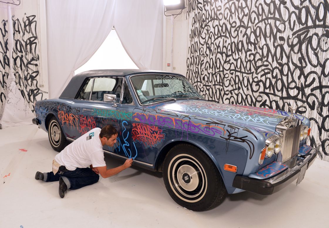 U.S. graffiti artist Jonone performs a painting on a Rolls Royce car owned by former Manchester United and France football player turned actor Eric Cantona during a television show.