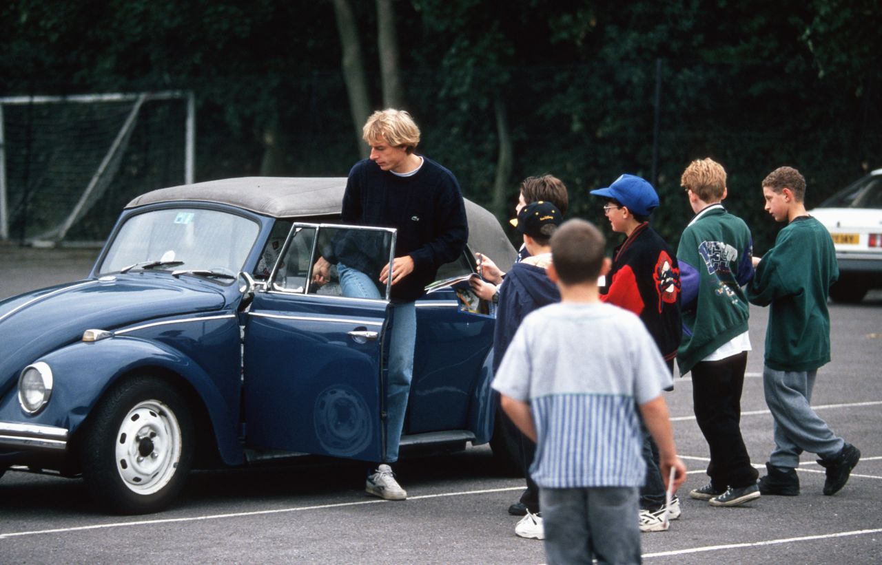 Former Germany star and current U.S. coach Jurgen Klinsmann gets into his Volkswagen Beetle while surrounded by onlooking schoolchildren.