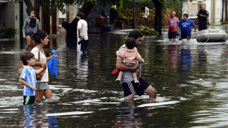 People wade through a flooded street after heavy rains in La Plata, Argentina, on Wednesday, April 3.