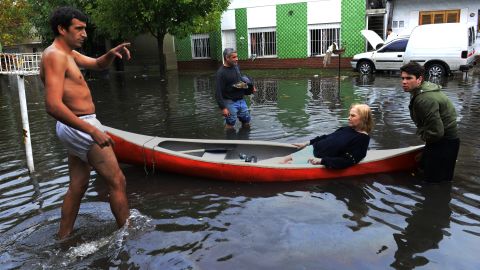 Neighbors help a woman with a canoe on April 3 in a flooded street of La Plata.