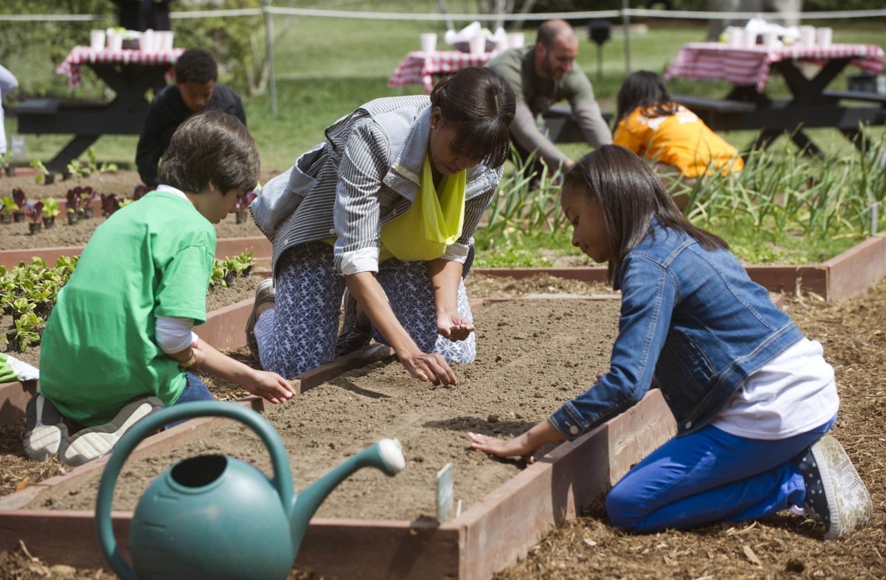 First lady Michelle Obama and a group of students from across the country planted the White House Kitchen Garden on the South Lawn on Thursday, April 4. Emilio Vega of Bradenton, Florida, left, and Ariana Docanto of Somerville, Massachusetts, plant wheat alongside the first lady.