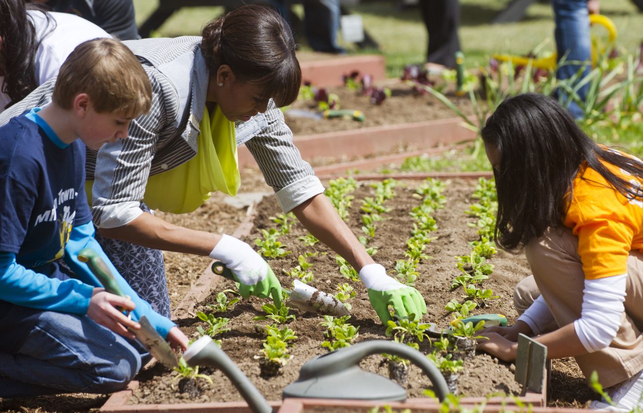 Nolan Deep of Milton, Vermont, left, and Kaila Bourne of Knoxville, Tennessee, help the first lady plant spinach.
