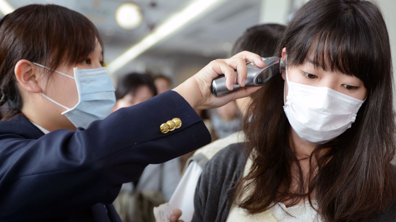 A passenger has her temperature checked by a CDC staff member at the entrance of Sungshan Airport in Taipei.