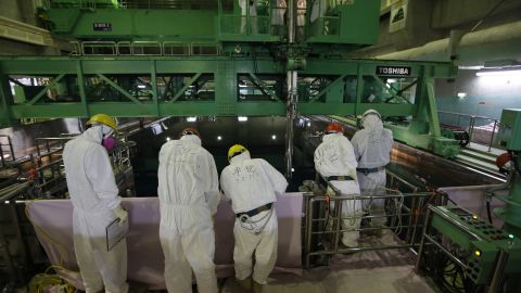 This file photo taken on March 6, 2013 shows workers wearing protective suits and masks next to the spent fuel pool inside the Common Pool Building.