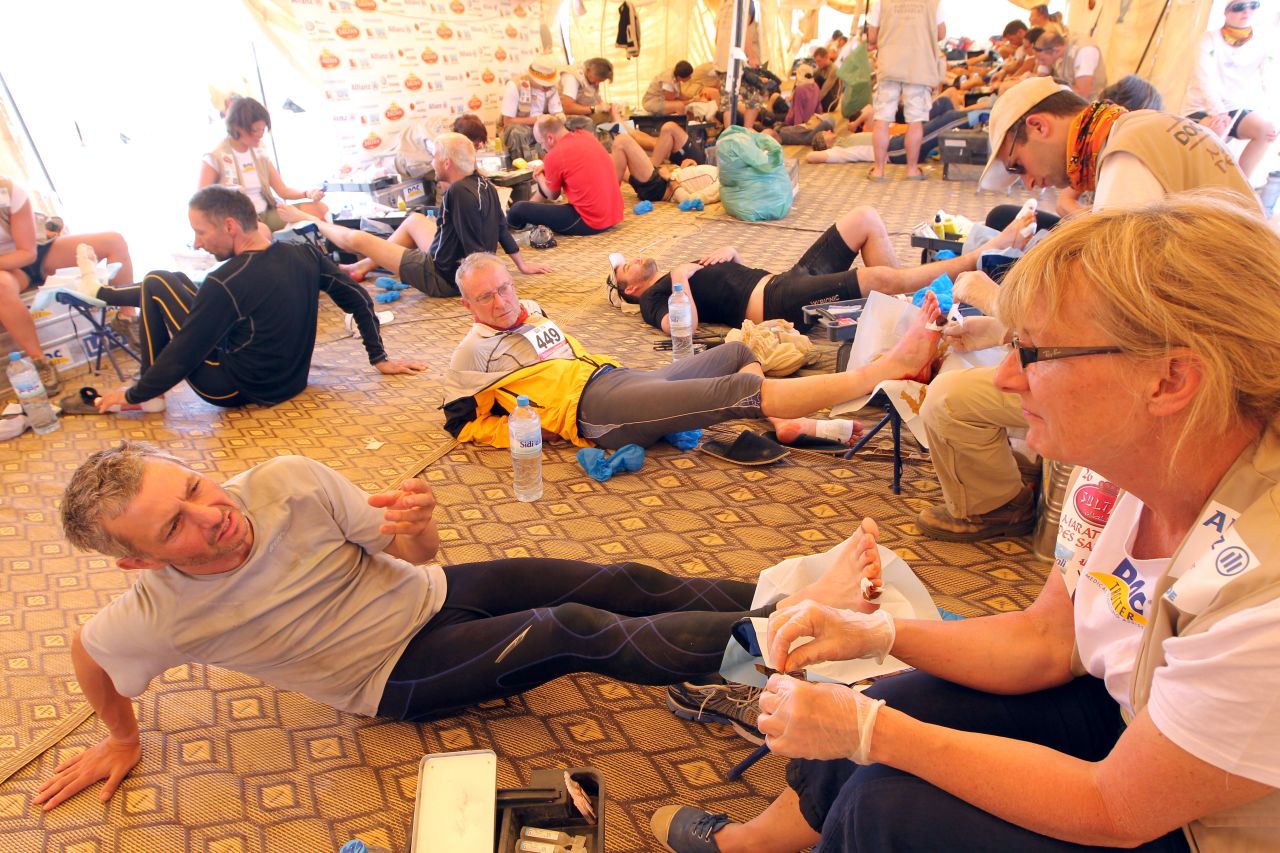 Competitors receive feet treatment at the end of a long stage. Putting the race together requires a plethora of resources, including 120,000 liters of mineral water, 6.5 kilometers of Elastoplast, 400 support staff, 270 berber and Saharan tents, 100 all-terrain vehicles, 19,000 compresses and 6,000 painkillers.