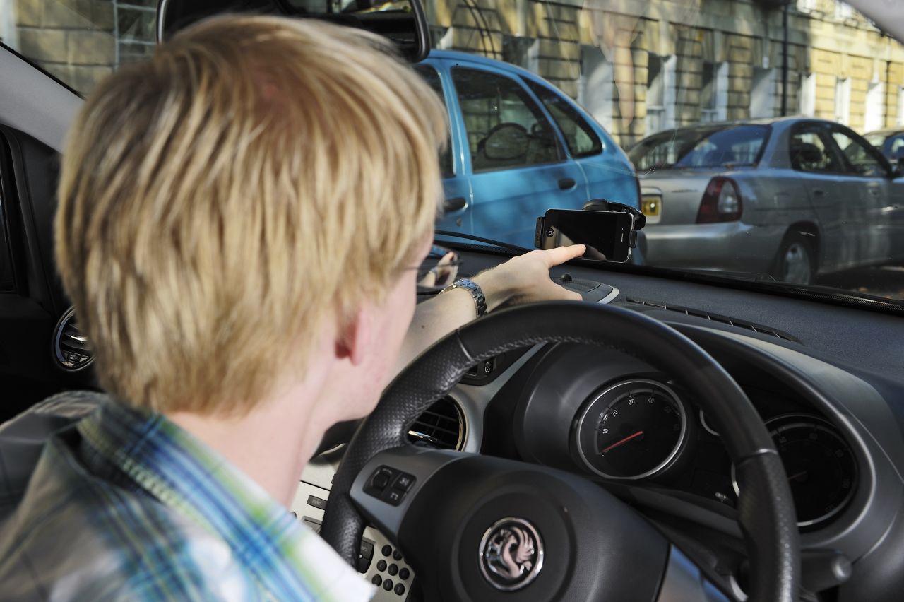 OK, you probably shouldn't be like this guy and play with your phone when driving. But the upcoming Moto X phone at least makes it a little safer. The Moto X lets you speak voice commands to your phone without touching it and will read your text messages aloud.